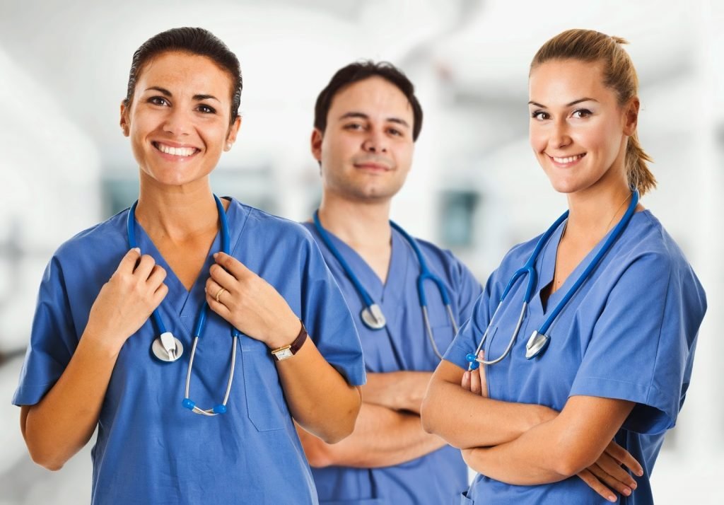 Personal de enfermería con uniformes de distintos colores en un pasillo de hospital